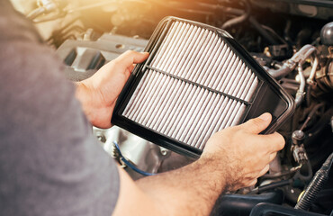 A auto mechanic carries a replacement car air filter for car engine maintenance