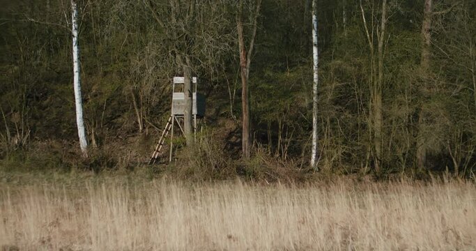 View of the hunting wooden watchtower on the edge of a grassy meadow. Slow panning camera movement