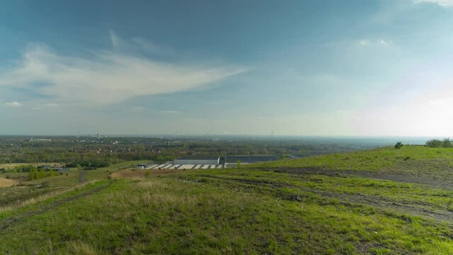 Small industrial townscape with wind  turbines from mining heap on vibrant sunny day, static time lapse view