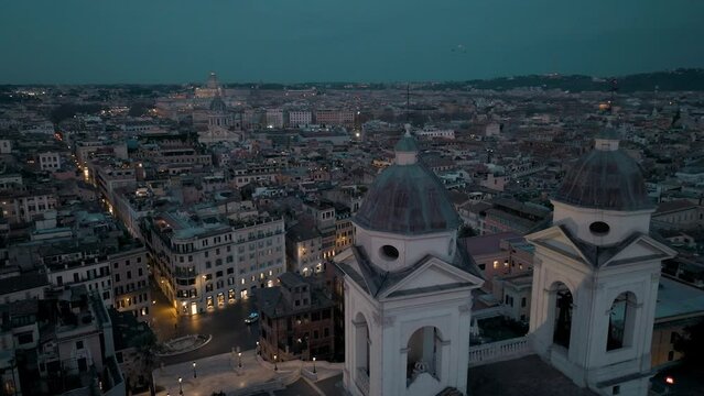 Aerial view around the towers of Trinita dei Monti overlooking the illuminated streets of Rome, Italy - circling, drone shot