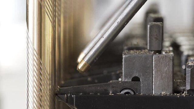 detailed metalwork of a machine that carves patterns into pieces of gold metal
