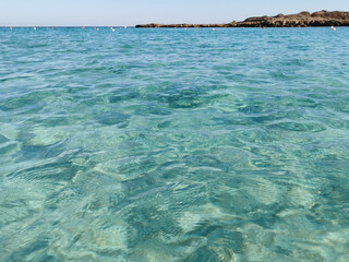 Fototapeta na wymiar Fig Tree Bay beach, crystal clear water, white sand at the bottom, small island off the coast.