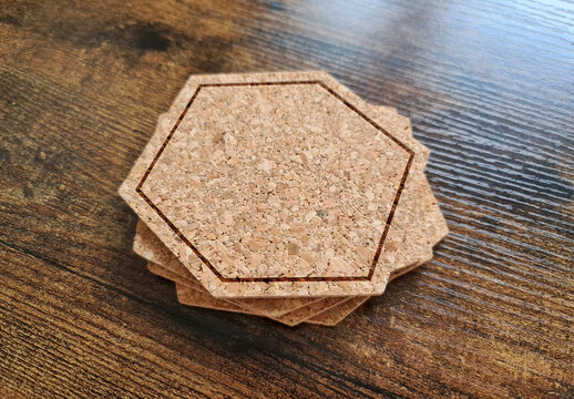 Blank stack coaster mockup with cork texture on wooden surface. Hexagonal drink pad pile template