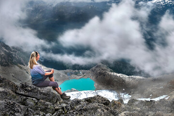 Woman cliff above glacier turquoise lake and clouds. Mountain view from above. Brandywine mountain. Vancouver. British Columbia. Canada