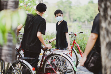 Obraz premium Teenager boy riding bicycle in the park with happy family