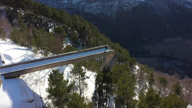 Top down rotating aerial of Stegastein viewpoint - First looking at edge with Aurland village below before rotating around to see Bjorgavegen road to snowy Aurlandsfjellet mountain behind