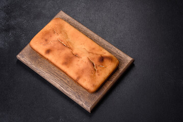 Baked rectangular cupcake with raisins and chocolate on a dark concrete background