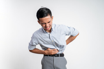 asian young man having stomachache holding his stomach with two hands on background isolated