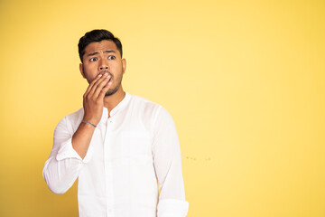 asian man wearing white shirt surprised with palms covering mouth with copyspace on isolated background