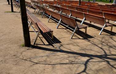 outdoor theater auditorium. Benches stacked in rows. adjacent. There is an alley between the wooden benches. park sand paths.