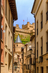 Fototapeta na wymiar Rustic medieval stone houses in a narrow street of the old town of Olite, Spain with a view onto the magnificent Royal Palace castle