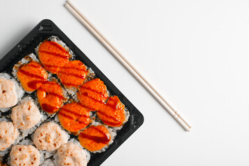 Japanese traditional sea food, Asian cuisine. Set of baked hot yaki maki rolls and chopsticks on white table. Top view, close-up