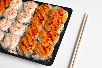 Japanese traditional sea food, Asian cuisine. Set of baked hot yaki maki rolls and chopsticks on white table, close-up