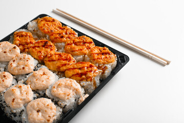 Delivery set of baked hot yaki maki rolls and chopsticks on white table, close-up. Japanese traditional sea food, Asian cuisine
