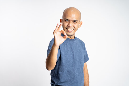 asian bald man smiling with okay gesture while standing on isolated background