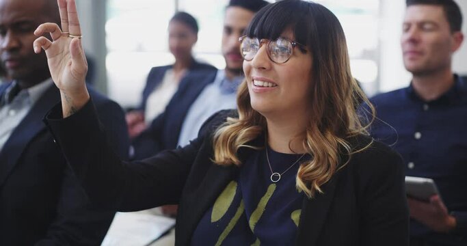 She has a valid point to bring across. Attractive confident young caucasian business woman raising hand to speak during a training seminar in conference workshop attended by colleagues and coworkers