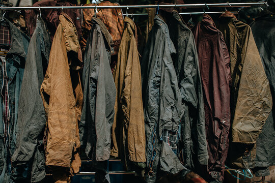 Collection of wax jackets on hangers in the shop. Many vintage men's jackets. Background and closeup texture of wax jackets.