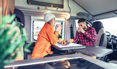 Friends having breakfast in a camper van in the morning - obrazy, fototapety, plakaty