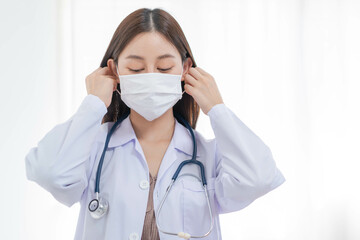 Doctor or physician asian young woman, wearing white coat, stethoscope and medical face mask to protect disease, prevention virus pandemic of covid-19, portrait isolated on background. healthcare.