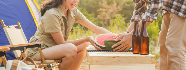 Cheer up, Pretty asian young woman, girl clap hand, sitting next to tent while man peel watermelon on table. Adventure couple, people camping in forest. Activity, lifestyle nature on holiday concept.