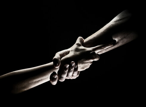 Two trength ands. Helping hand to a friend. Rescue or helping gesture of hands. Concept of salvation. Hands of two power people at the time of rescue, help. Isolated on black background.