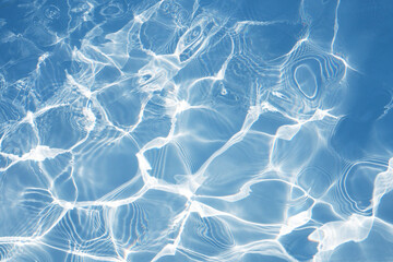Blue water surface with bright sun light reflections, water in swimming pool background