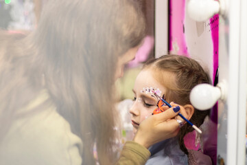 selective focus. A makeup artist works. childrens makeup face paint drawings Girls face painting. Little girl having face painted on birthday party. closed eyes. High quality photo