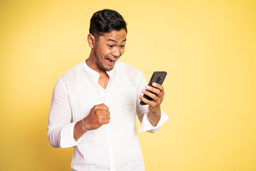 happy asian young man looking at the screen of a mobile phone on isolated background