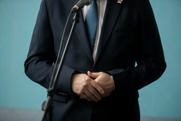 Press conference with media microphones held in front of business man, spokesman or politician