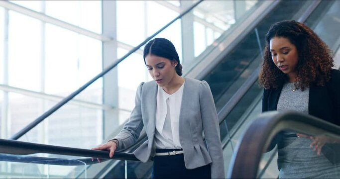 I'm glad I bumped into you. Two attractive ambitious confident young business women talking and discussing business ideas while standing on a moving escalator travelling down in a corporate workspace