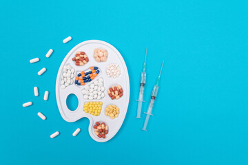 Global Pharmaceutical Industry and Medicinal Products - Different Colored Pills, Tablets and Capsules on White Art Palette with Syringe Lying on Blue Background, Flat Lay