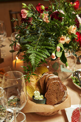 romantic dinner. the table is decorated with flowers and a burning candle in the restaurant. basket with sliced bread and snacks on the table
