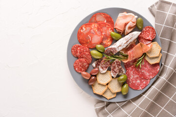 Assortment of different meat snacks, charcuterie plate with different types of sausages - salami, bresaola, proscuitto served. Traditional italian antipasti on white table background with copy space