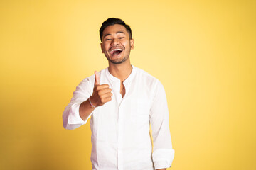 asian young man wearing white shirt laughing with thumbs up on isolated background