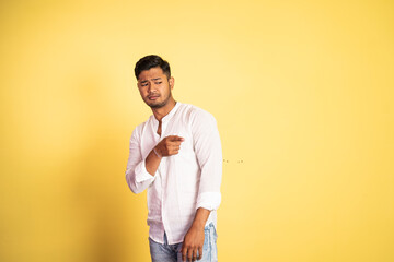 young asian man wearing white shirt with disdain expression pointing finger on isolated background