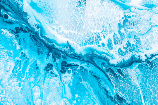 Liquid art texture with pouring colors. Fluid backdrop with flows and cells, waves. Abstract background with splatter inks. Blue colors mixes on macrophotography picture.