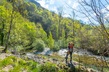 Fototapeta na wymiar A young mother with a backpack looking at the Sella river between the Tornin to the Olla de San Vicente, near Cangas de Onis. Asturias. Spain