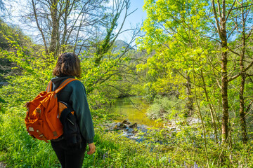 A young woman with a backpack looking at the mountains and the Sella river between El Tornin a la Olla de San Vicente, near Cangas de Onis. Asturias. Spain