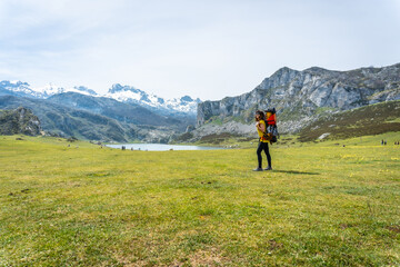 Fototapeta na wymiar A mother with her child in her backpack at Lake Ercina in the Lakes of Covadonga. Asturias. Spain