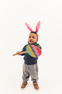 Small toddler with cartoon Easter egg and bunny ears looks excited and happy. High quality photo