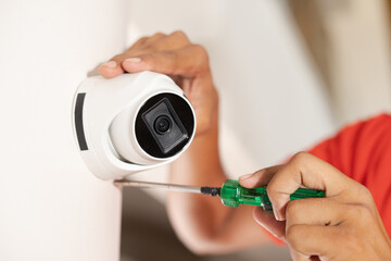 Close up shot of technician fixing cctv camera on wall at home - concept of safety, professional...