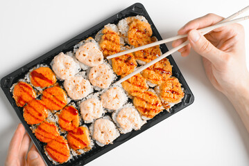 Japanese traditional sea food cuisine. Close-up of hand eating set of hot rolls with chopsticks. Close-up, top view