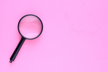 Black magnifier on a pink background.
