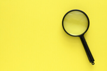 Black magnifier on a yellow background.