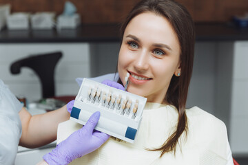 Selection of the correct tooth color for professional cosmetic whitening at the dentist. the doctor...
