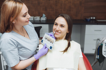 Selection of the correct tooth color for professional cosmetic whitening at the dentist. the doctor...