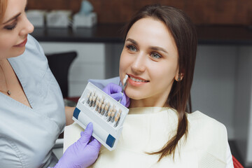 Selection of the correct tooth color for professional cosmetic whitening at the dentist. the doctor...
