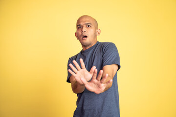 asian bald young man rejecting offer with both palms on isolated background