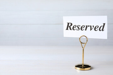 Elegant sign RESERVED on white wooden surface, space for text. Table setting element