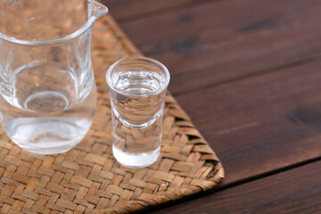 Small glass of height liquor on bamboo mat cushion